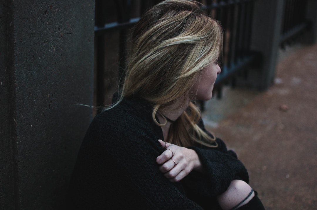 woman squatting and looking away from camera during daytime