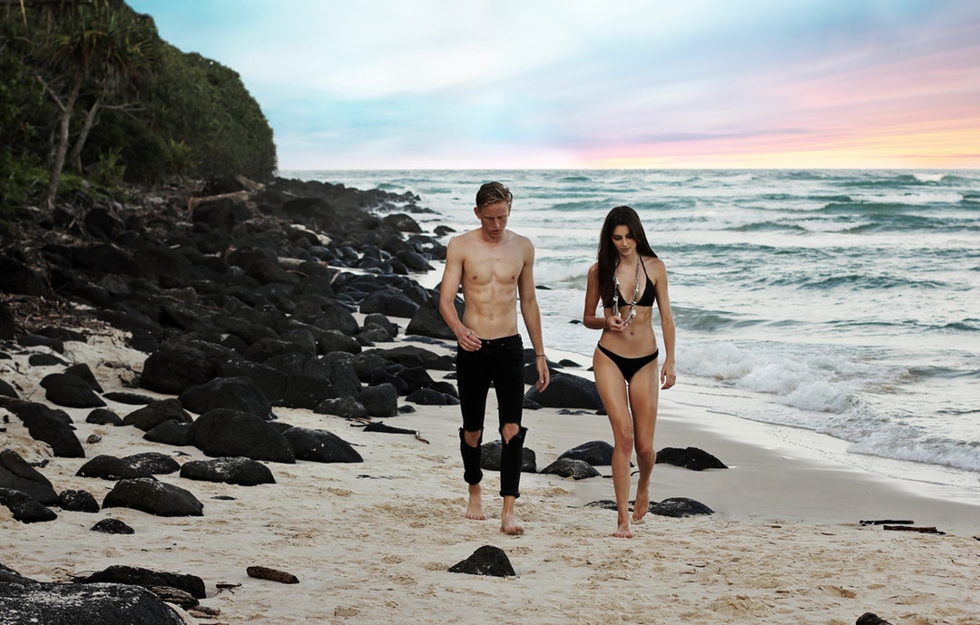 Couple in swimsuits walking on the sand beach