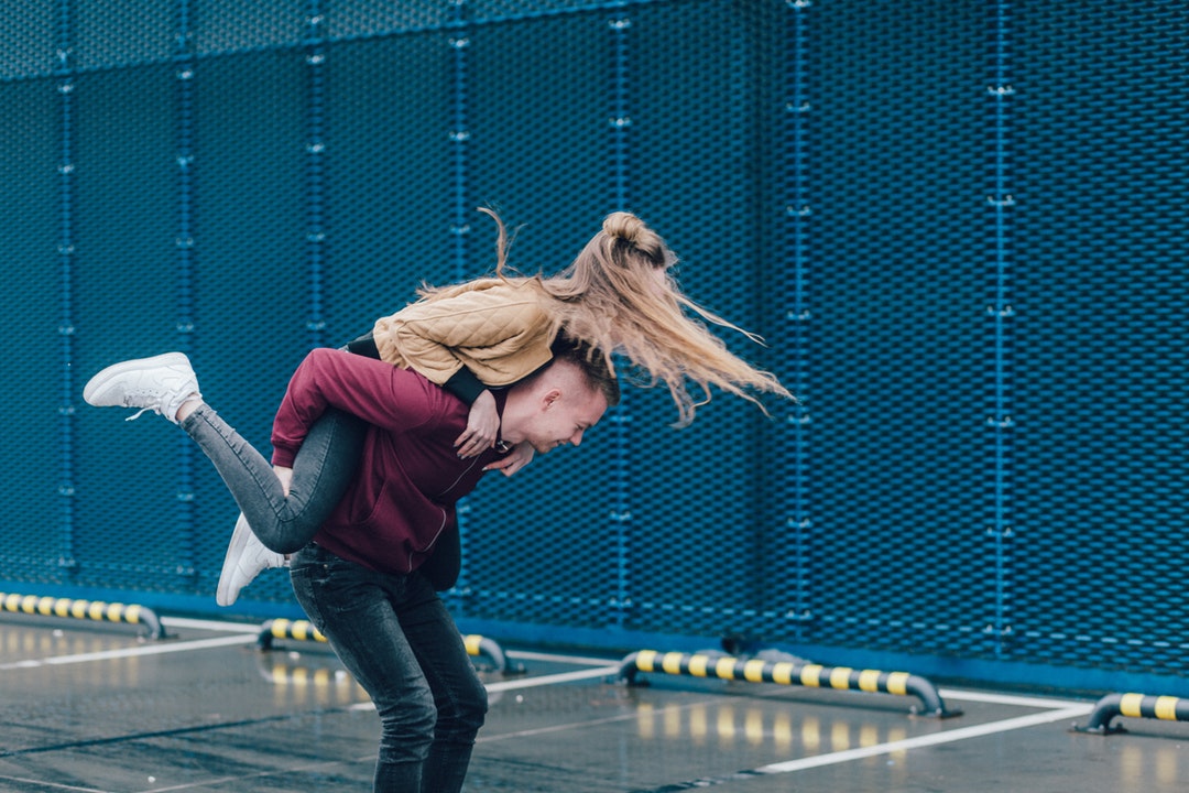 Happy young couple playfully jumping on each other's back