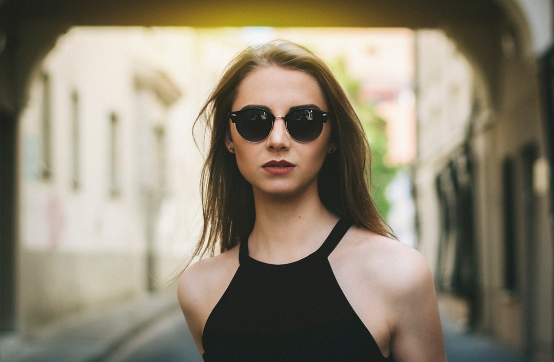 Woman looking forward in sunglasses and a black halter top