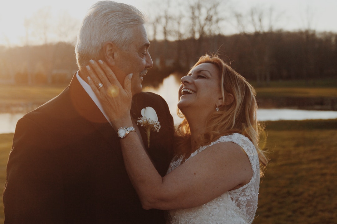 Older couple, just married and laughing with lake in background