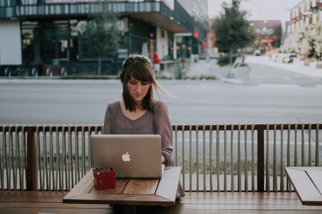 A woman working on a laptop outside a coffee store