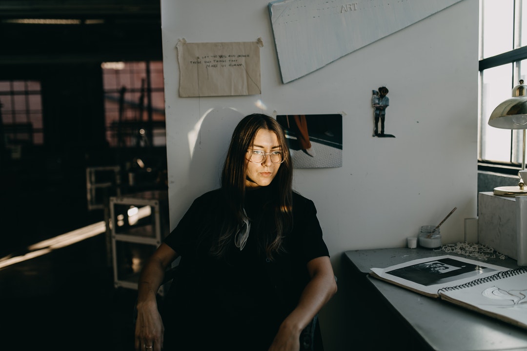 Young attractive dark haired woman sitting and contemplating in art workshop in Springfield