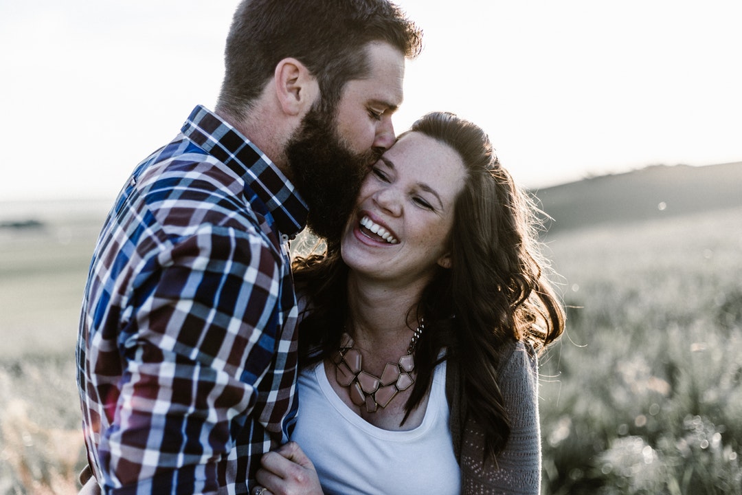 Boyfriend kissing his smiling happy girlfriend on the cheek