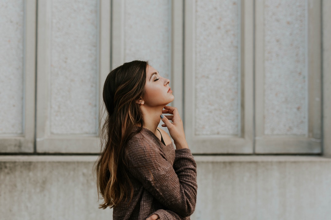 Woman closing her eyes and relaxing on a walk outside