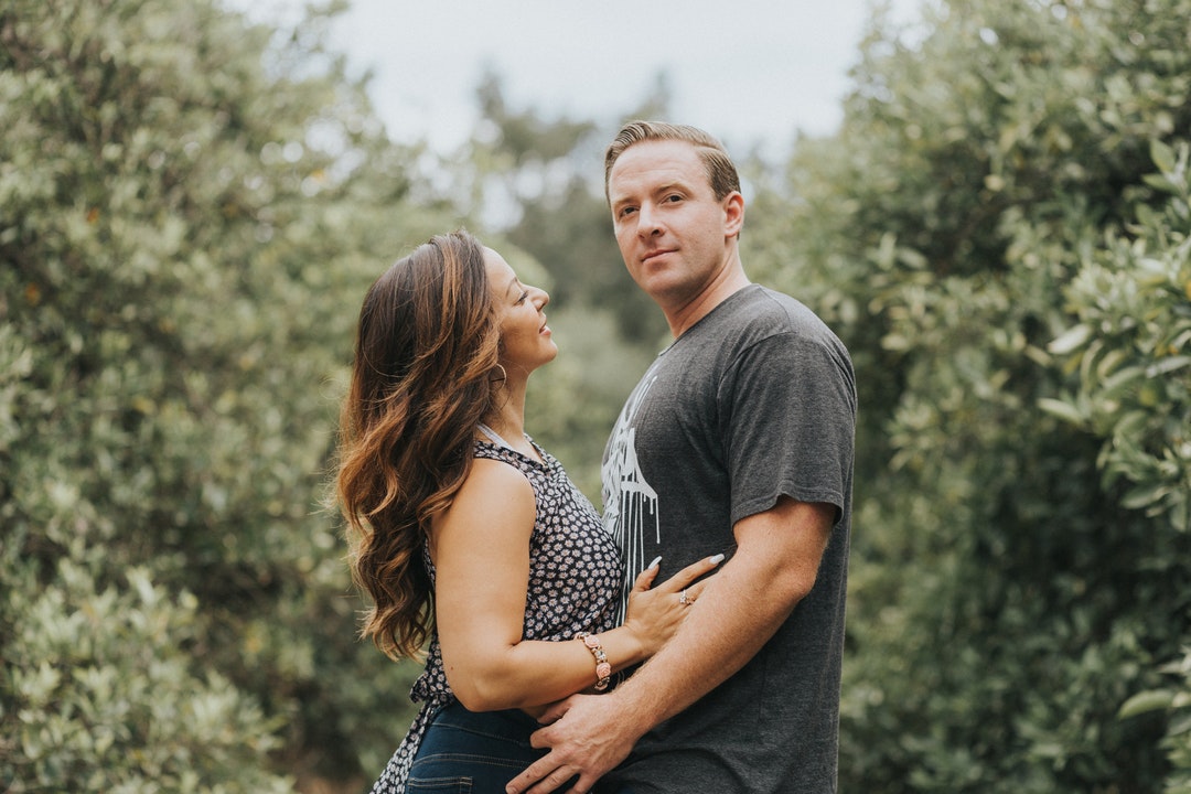 Happy couple embracing in a field of trees