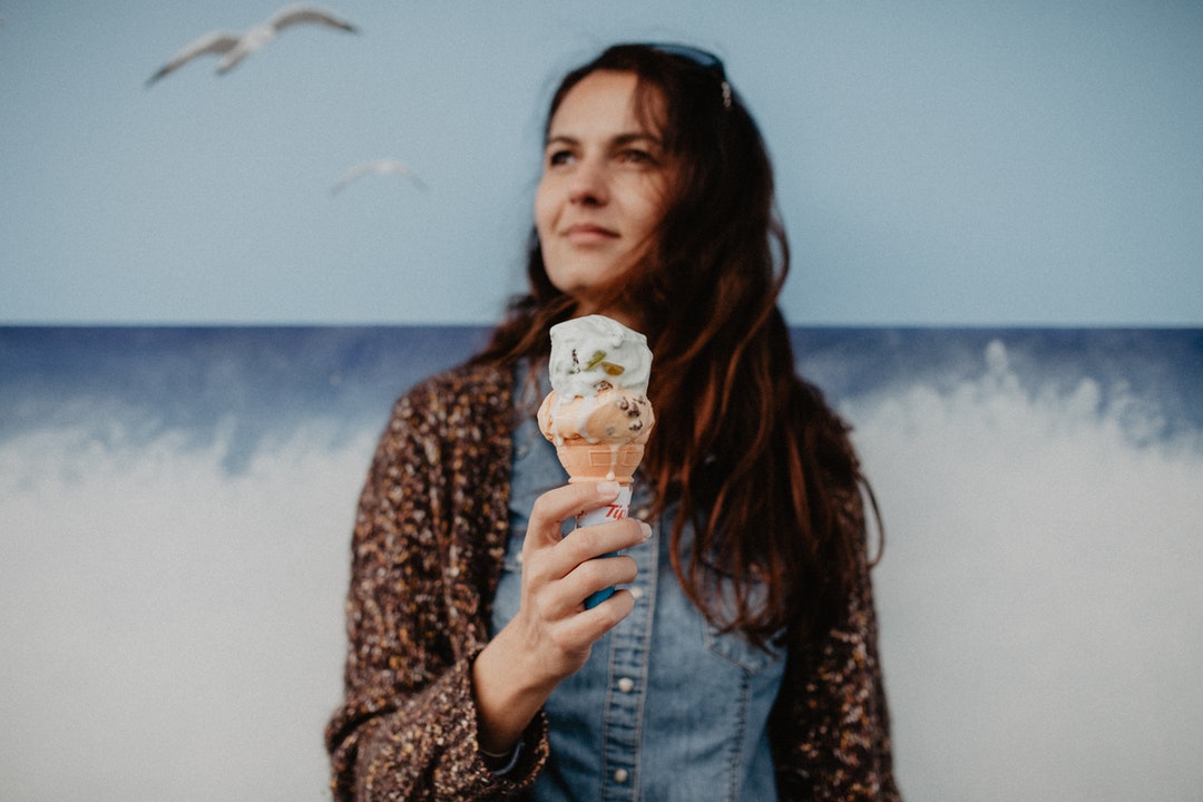 A woman eating ice cream by the water.