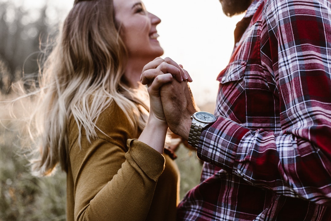 A man and woman holding hands together and looking into each other's eyes.