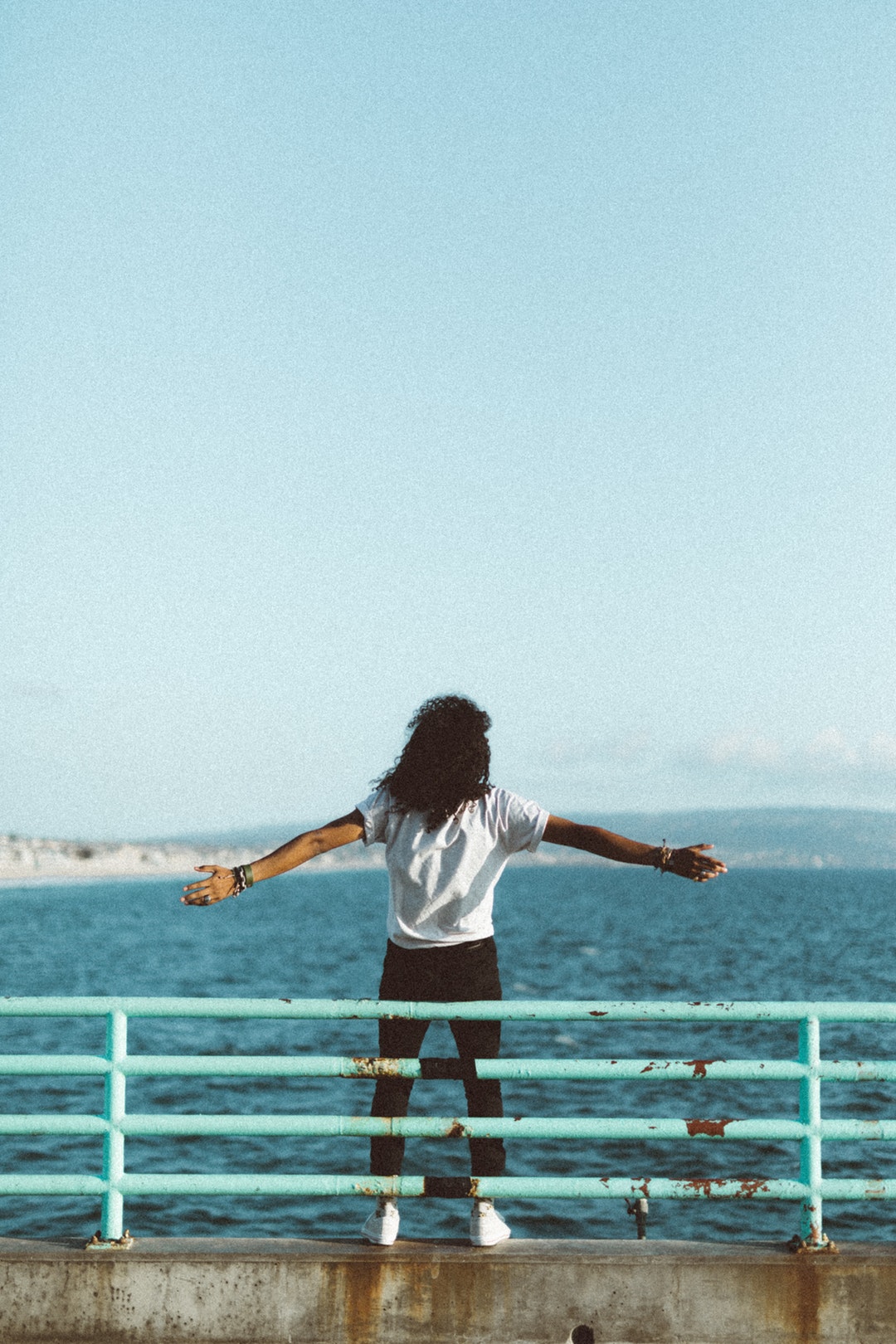 woman standing in front of sea under clear blue sky