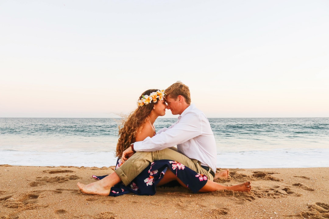 woman and man sitting face to face on seashore