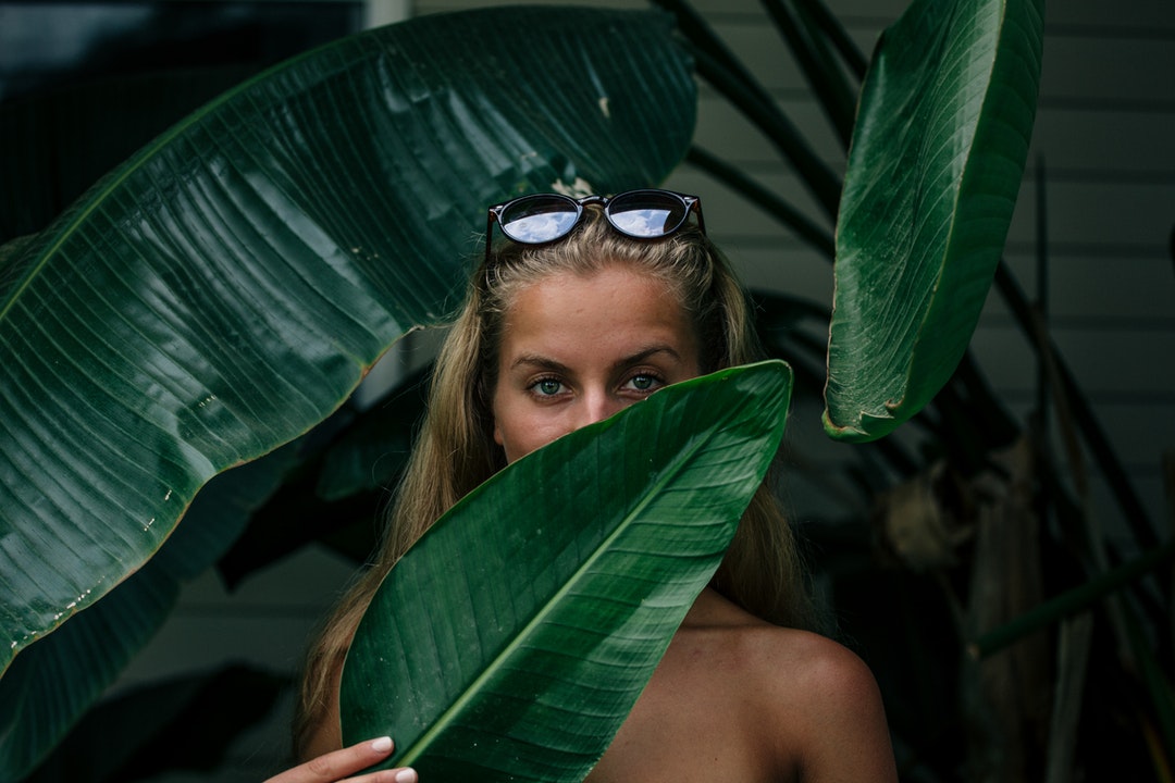 woman covering her face with green leaf