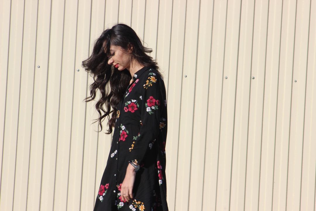 woman standing beside beige wall during daytime