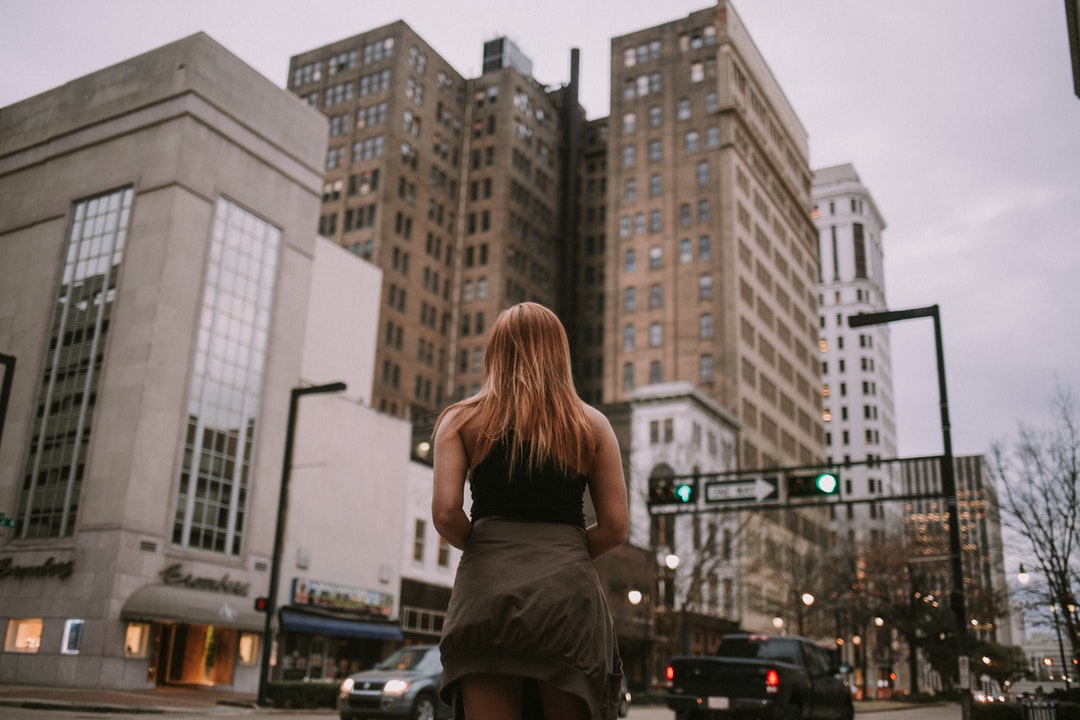 woman standing near cars and concrete building during daytime