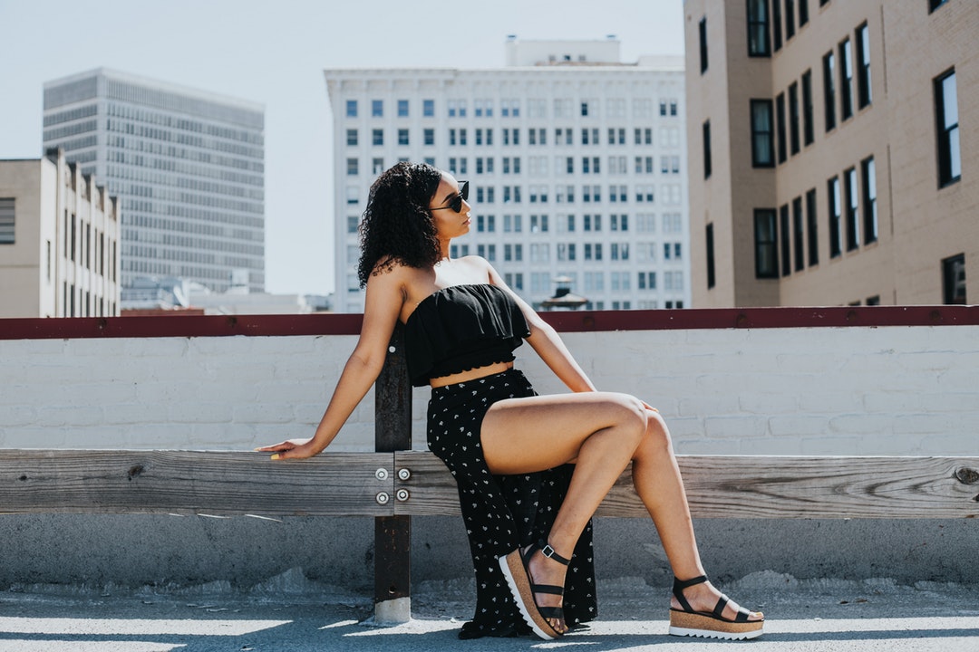 woman sitting near white concrete fence