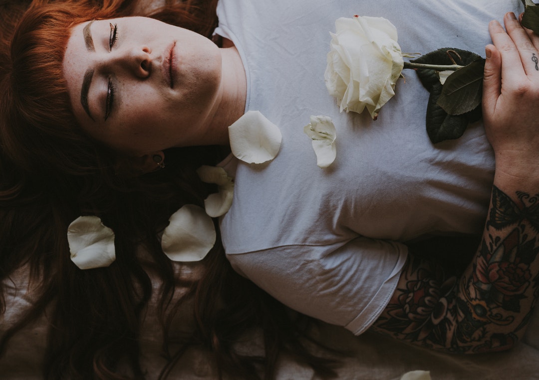 woman sleeping holding white rose flower