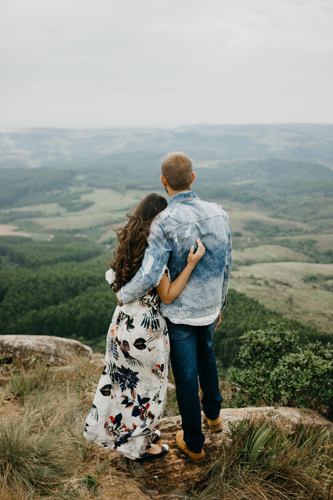 man and woman standing on cliff during daytime