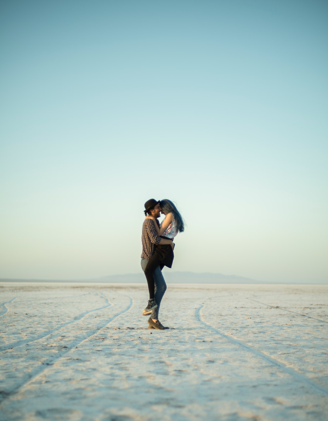 man carrying woman while standing on snow road