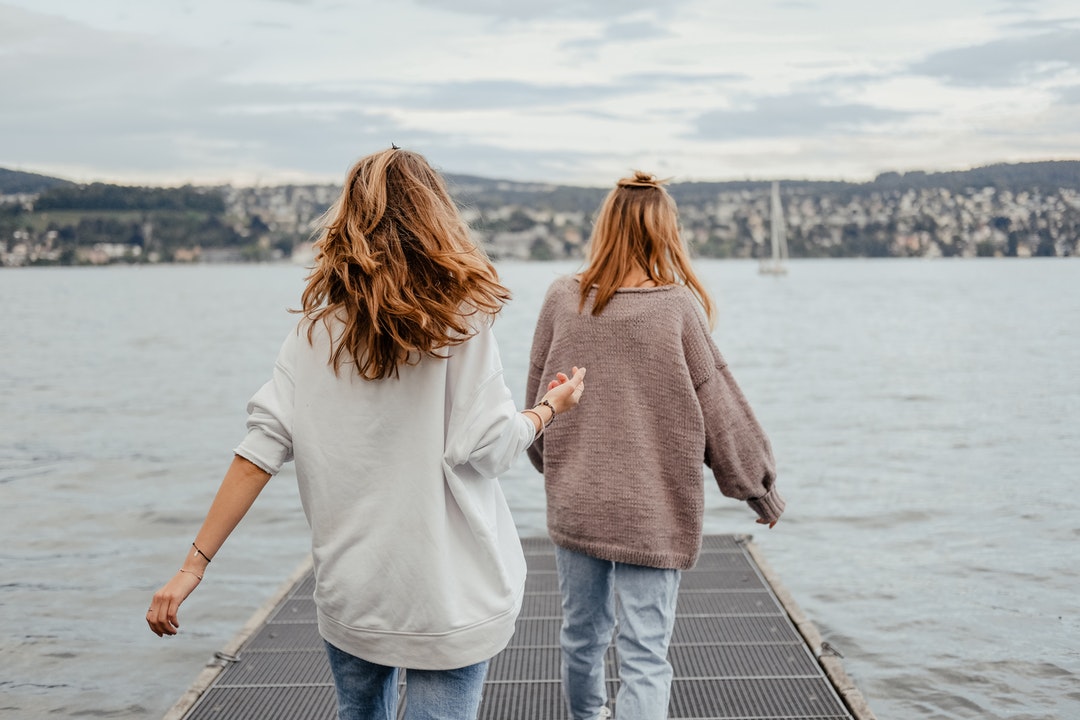 two women standing on dock front of sea at daytime