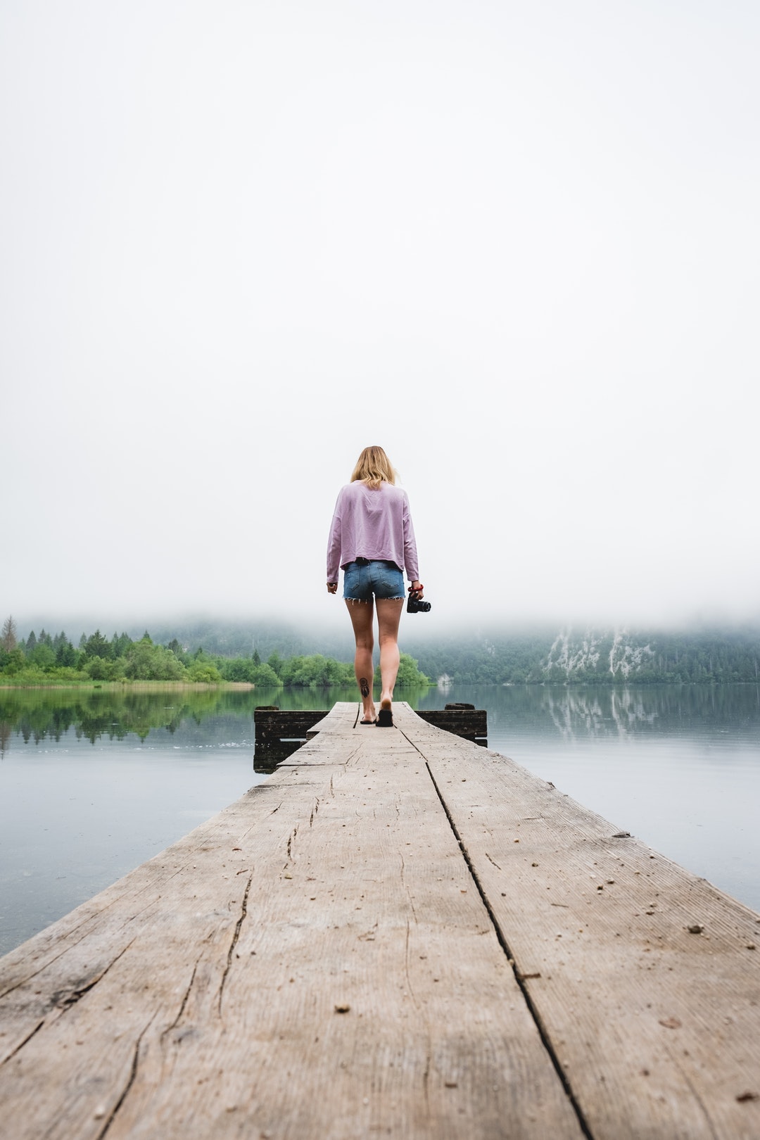 woman walking on dockside beside body of water