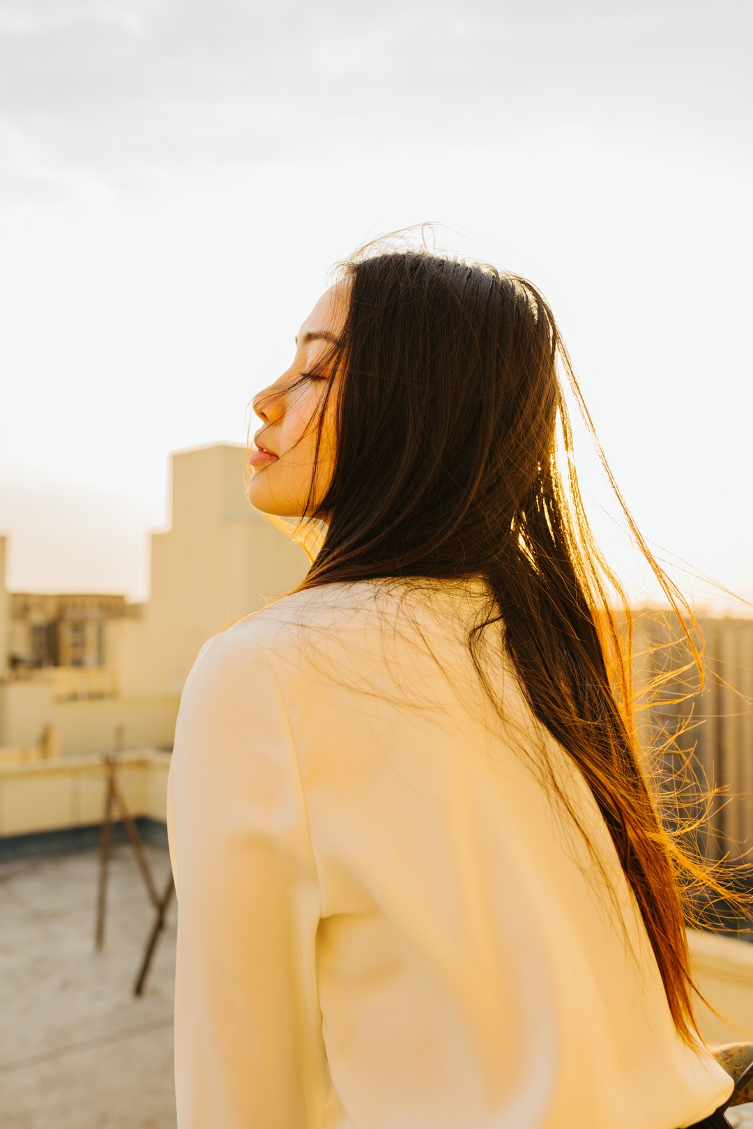 back view of woman wearing white shirt closing her eyes