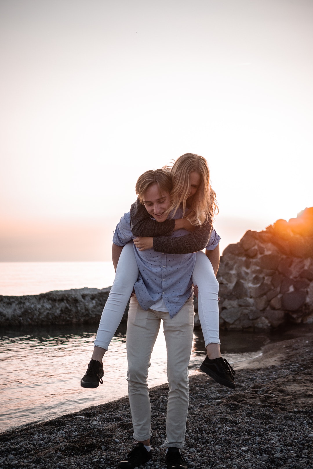 woman hop in on man's back on beach shore