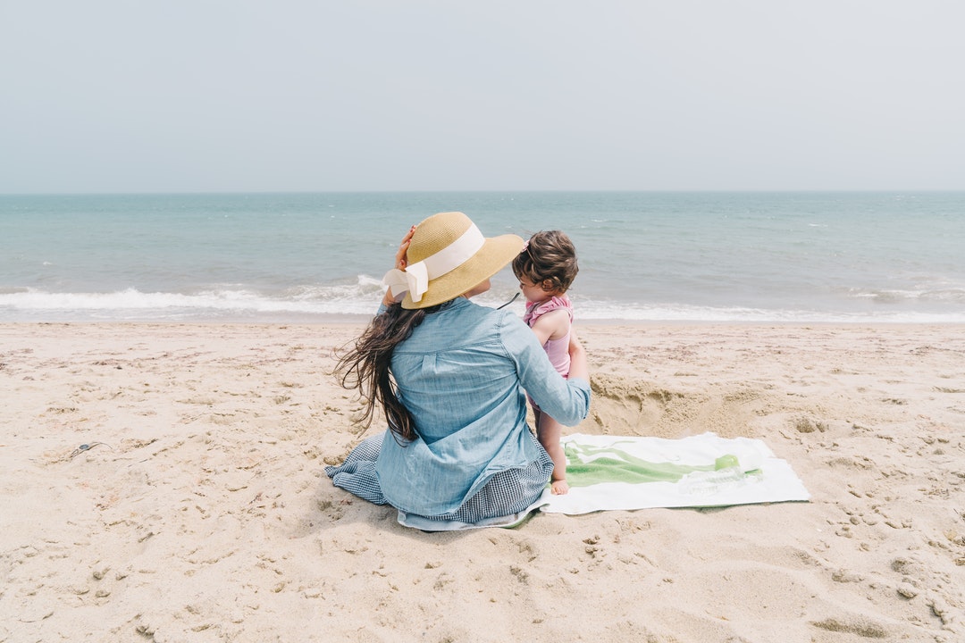 woman holding toddler on front seashore