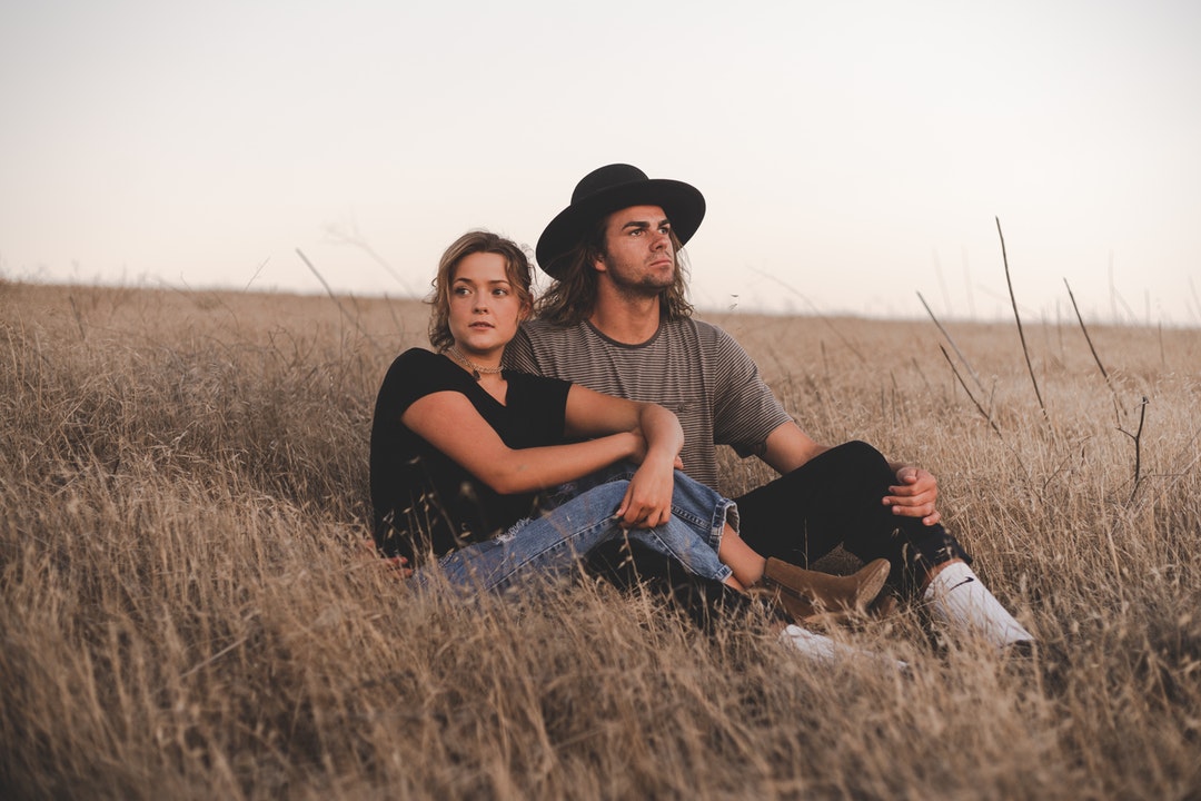 woman and man sitting on wheat field