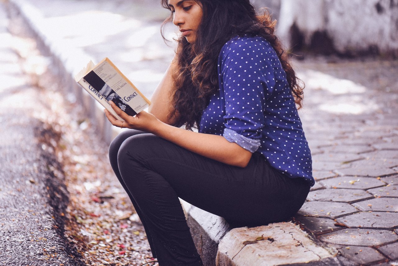 girl reading on the sidewalk