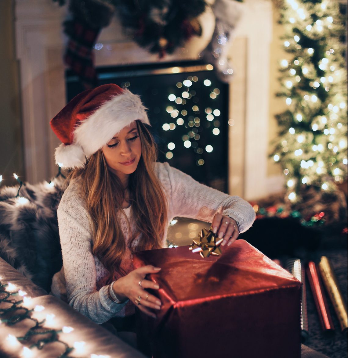 woman wrapping present in santa hat