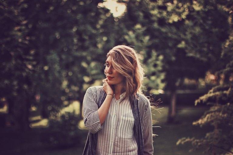 woman standing in forest looking wistful