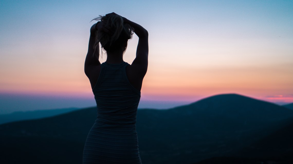 girl standing in front of a sunrise