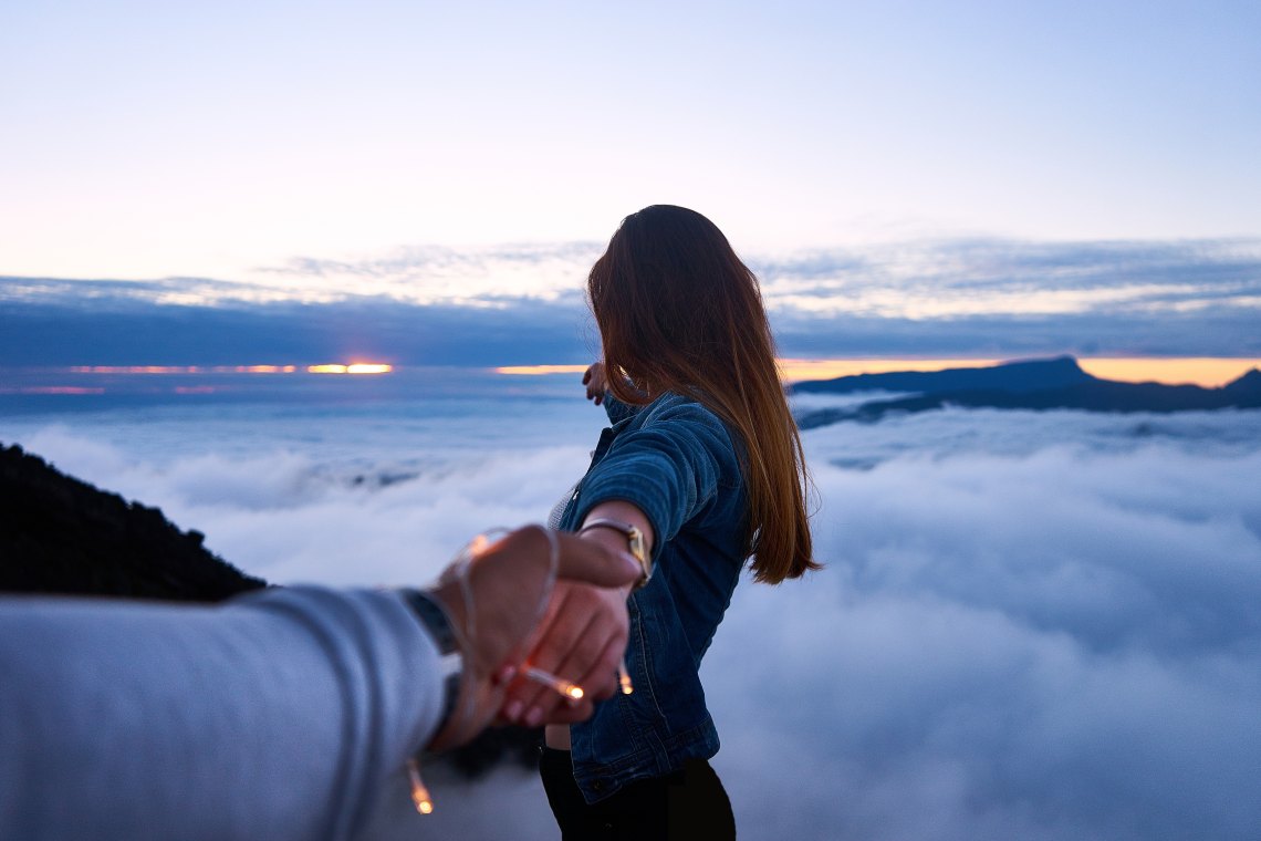 couple holding hands over beautiful clouds