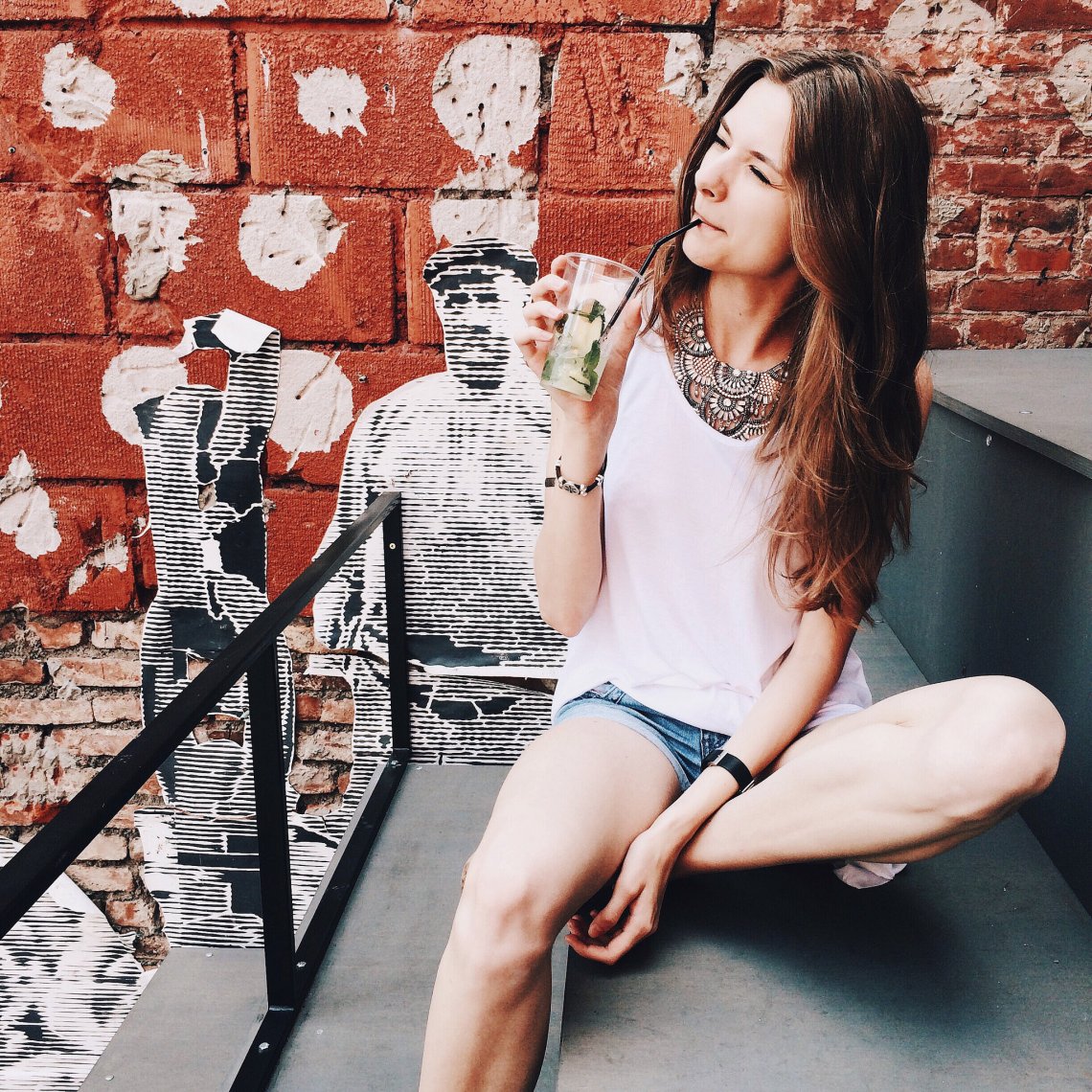 girl sipping on fruity drink relaxing by street art