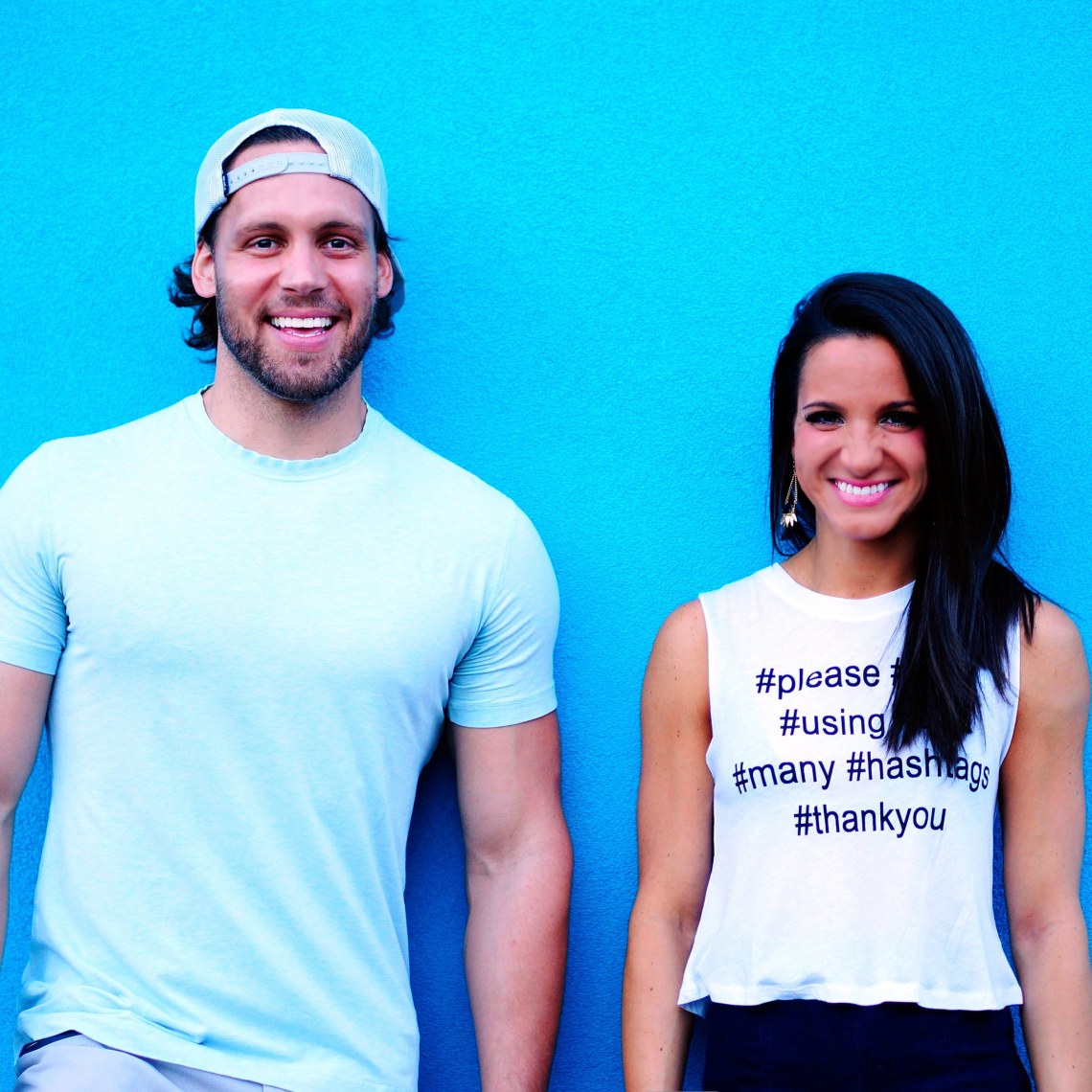 couple or friends hanging out against blue wall with hashtag shirt on