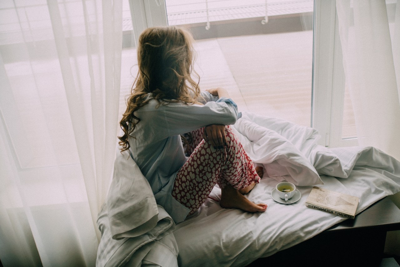 girl in a nook with a window and a book