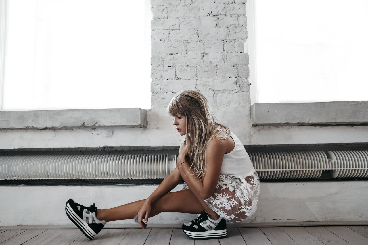 Girl in a sheer white skirt and heavy chunky sneakers contemplating life, thoughtful, pensive, brave