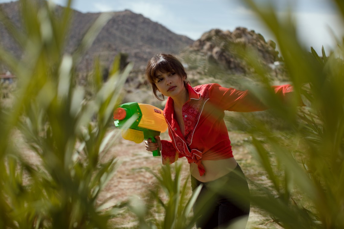 girl with water gun hiding in plant