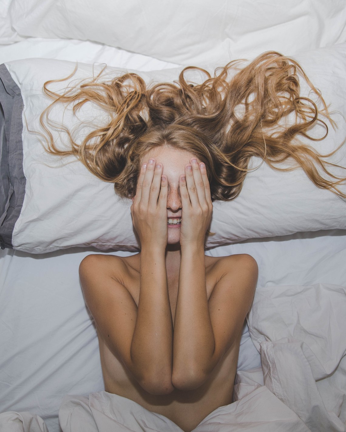 woman laying happy with hands over face