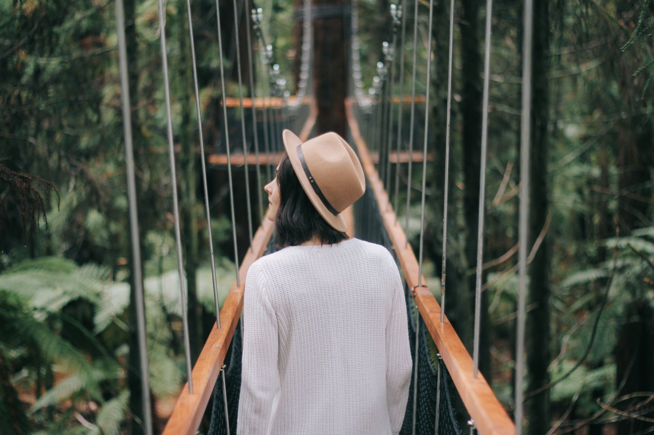 Woman walking over bridge in forest