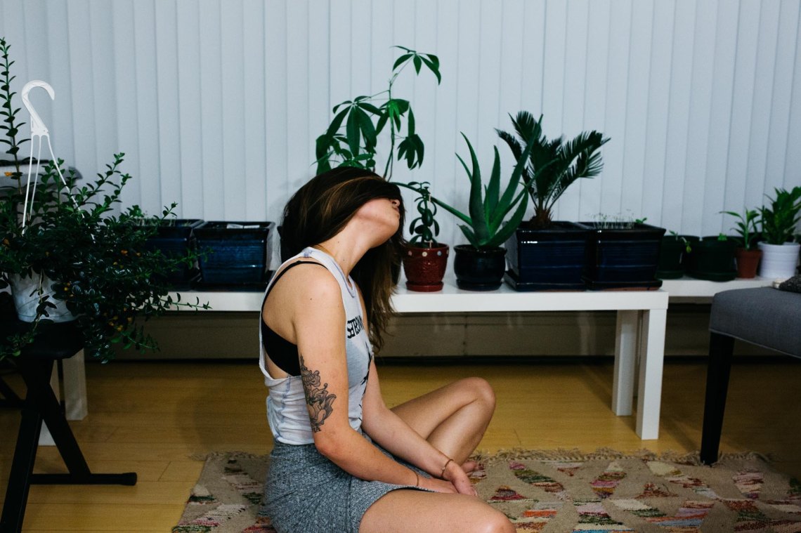 girl sitting on the floor of an apartment near plants