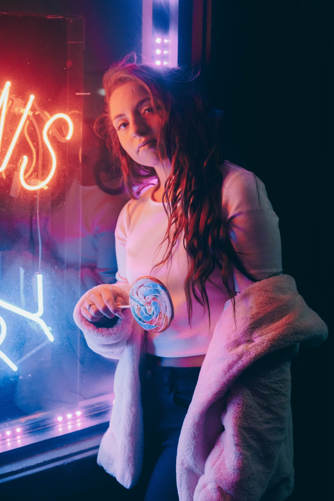 girl by neon with a lollipop