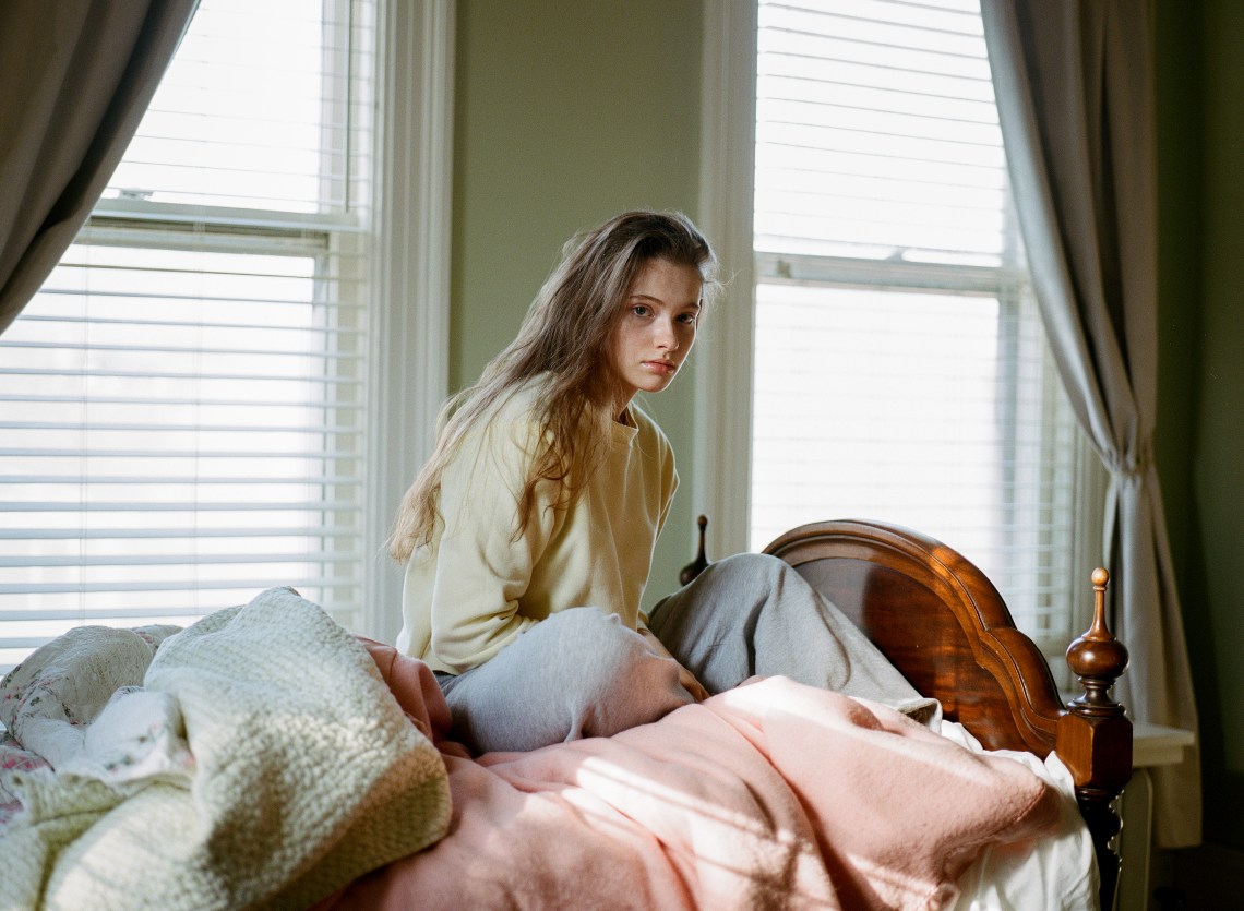 woman sitting on bed looking contemplative