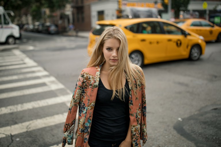 woman walking in street wearing peach cardigan