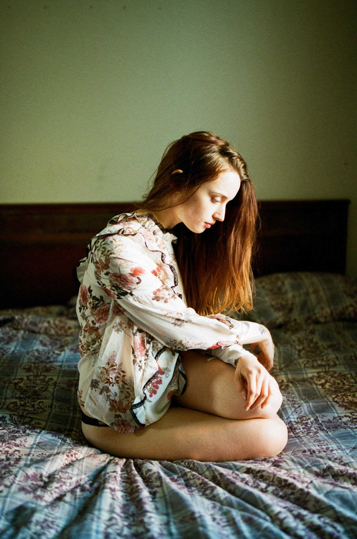 woman sitting on bed looking thoughtful