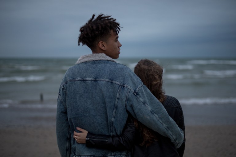 young couple arms around each other on the beach