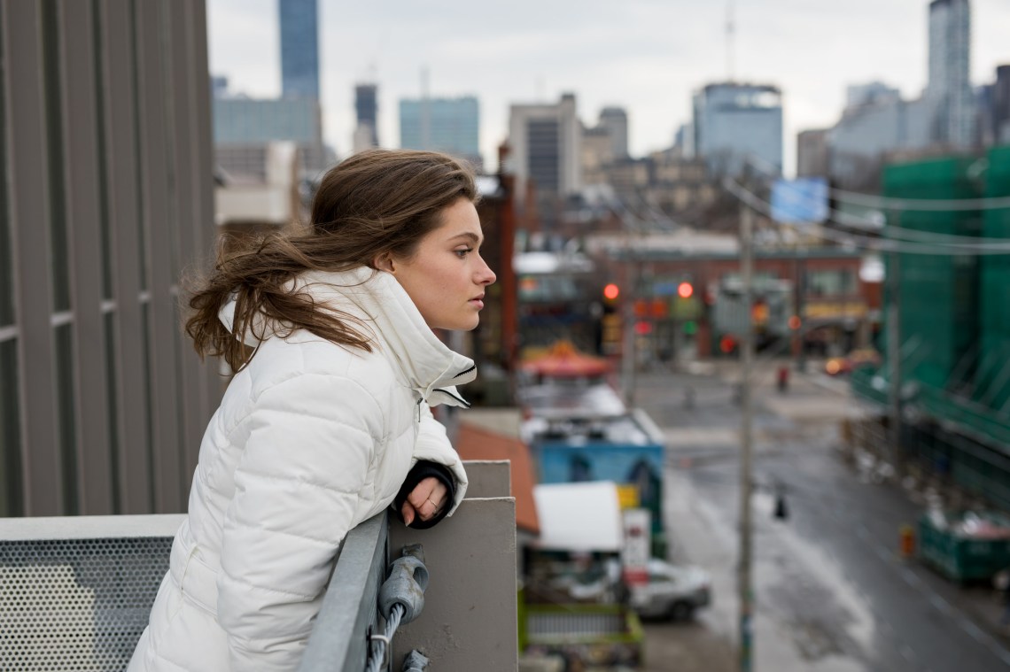 girl in a white coat looking over the city