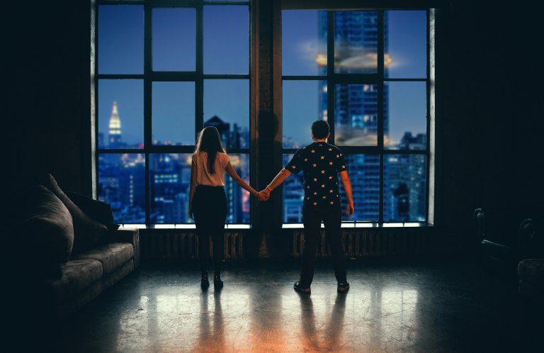 couple facing window holding hands