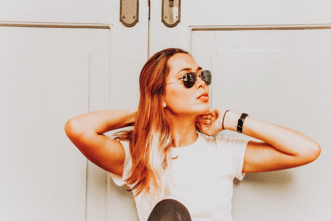 Woman sitting in sunlight against door