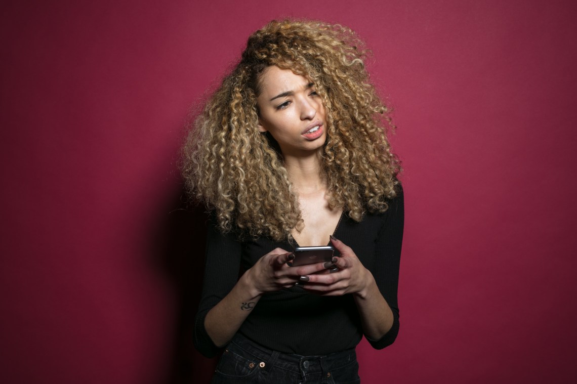 A woman looks up from her phone, confused and annoyed at the stupid person texting her