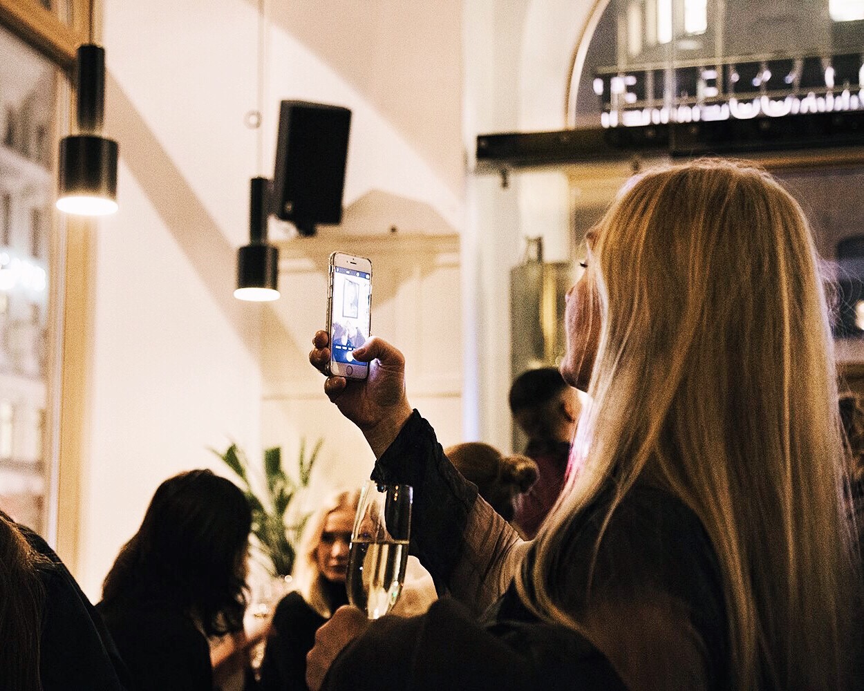 woman drinking champagne holding phone